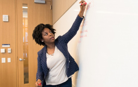 Teacher writing on white board with red marker