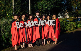 Doctoral students at the MIC Conferring Ceremonies holding an MIC sign