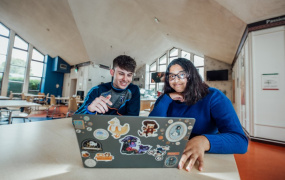 Male and female MIC students sitting in front of laptop