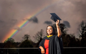 female graduate in cap and gown with rainbow at MIC Graduation 2024