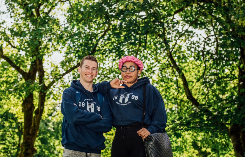 Male and female student standing in front of trees at MIC