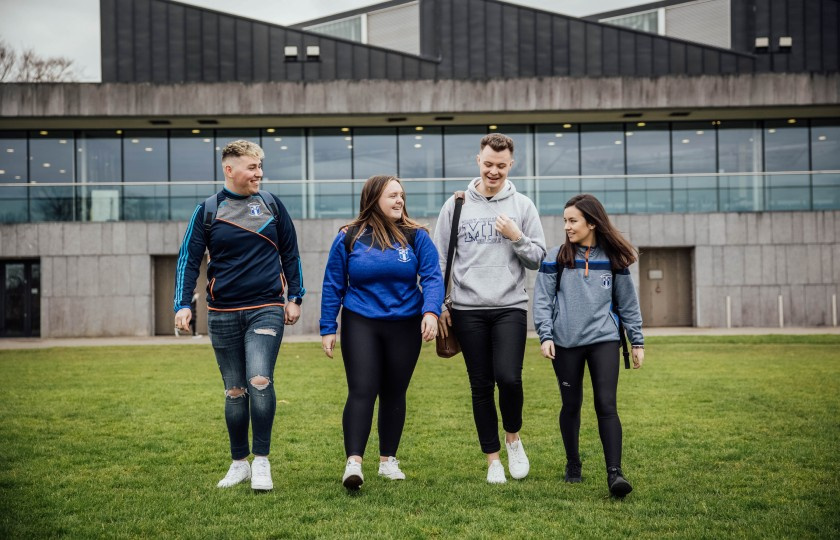 Four students walking in front of College building