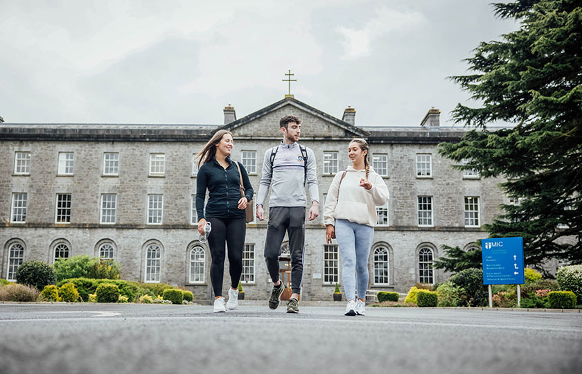 Three students walking in front of the Thurles campus main building