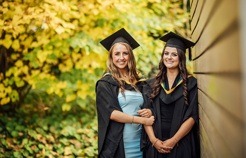 Two college graduates in their gowns and hats