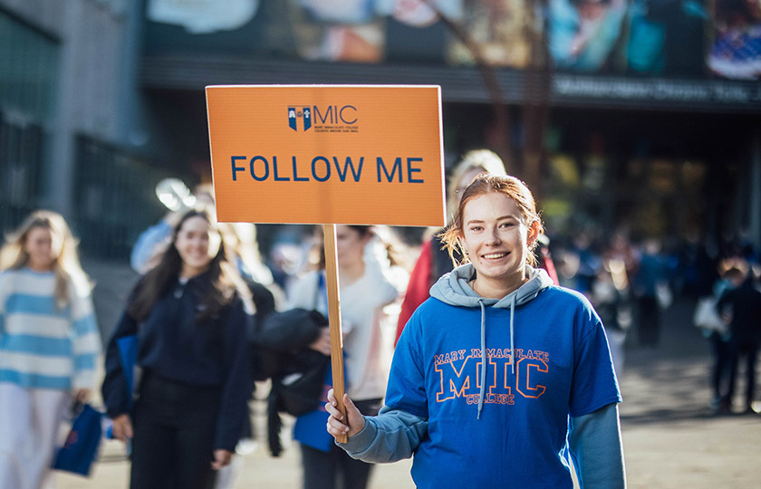 Student carrying a Follow Me sign at MIC October Open Day