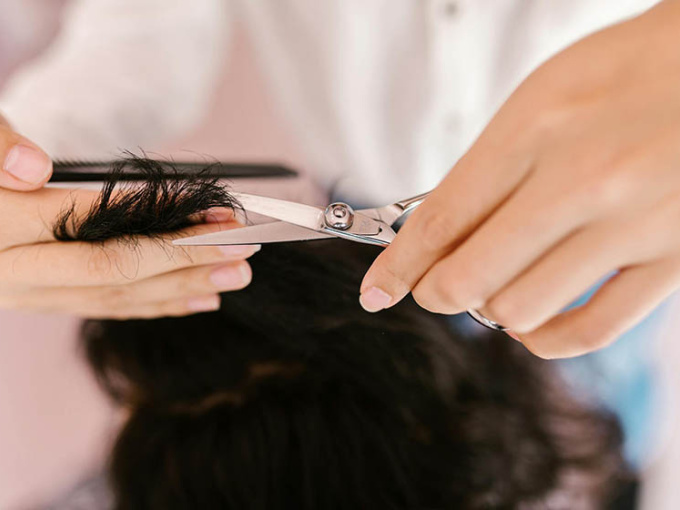 Person Cutting Hair Using a Silver Scissors