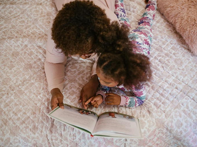 Parent and child reading together on a bed